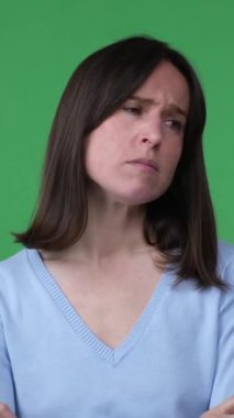 Yeşil arka planda hüzün ve melankoliden muzdarip orta yaşlı bir kadının portresi. Hüsran kavramı, depresyon. Dikey video.