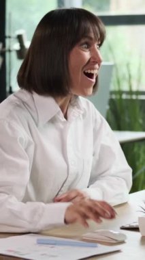 Şanslı kadın serbest yazar, ofiste masaüstü bilgisayarıyla çalışırken vay canına diyerek iyi haberleri kutluyor. Dikey video.