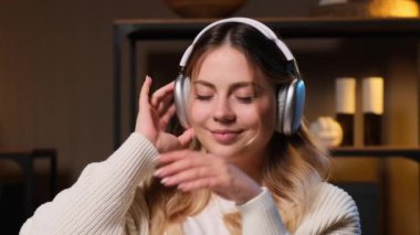 Dikkatsiz beyaz kadın kulaklıkla müzik dinliyor, akşam evindeki kanepede dinleniyor. Hafta sonu eğlencesini ya da boş zamanlarını ses eğlencesiyle geçirmek.