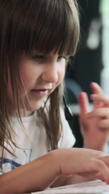 Anaokulu konsantre ve odaklanmış beyaz kız kulaklıkla konuşuyor, klavyede daktilo çalıyor, ofiste çalıyor. Dikey video.