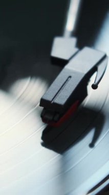 Dönüş plağı ve pikap iğnesiyle retro vinil çalarken yakın çekim. Eski müzik eğlence ekipmanları konsepti. Dikey video.