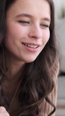 Evde dizüstü bilgisayar kullanarak çevrimiçi eğlenceye girişen mutlu beyaz kadın. Boş zaman harcamak, sosyal medyada mesajlaşmak. Dikey video.