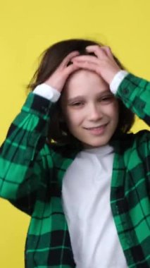 Sarı arka planda tek başına duran şık ve iyimser beyaz bir gencin portresi. Çocuk kişiliği, bireysellik. Dikey video.