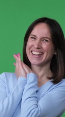 Kaygısız ve neşeli orta yaşlı beyaz kadın yeşil arka planda gülüyor ve eğleniyor. Mutluluk ve tatmin kavramı. Dikey video.