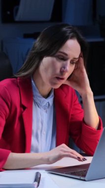 Uykusuz, orta yaşlı, serbest çalışan, dizüstü bilgisayarla çalışan ve gece yarısı ofisinde esneyen bir beyaz. Aşırı çalışma ve yorgunluk kavramı. Dikey video.