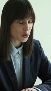 Ofiste çalışırken çevrimiçi video görüşmesine katılan mutlu bir beyaz kadın ressamın portresi. İş konuşması konsepti. Dikey video.