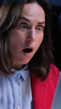 Memnuniyetsiz, beyaz, orta yaşlı bir kadının portresi akşam ofisinde çalışırken soruna ya da hataya şaşırmış. Dikey video.