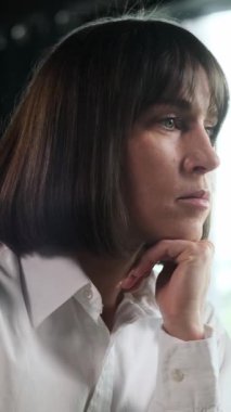 Ofiste çalışan düşünceli, beyaz, orta yaşlı bir kadının portresi. Gelişmekte olan bir proje veya girişim kavramı. Dikey video.