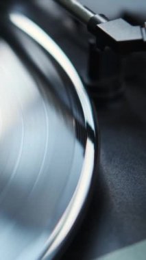 Retro çalar üzerinde plağa iğne batıran bir kadının yakın çekimi. Analog, klasik müzik ekipmanı konsepti. Dikey video.