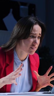 Akşam ofisinde dizüstü bilgisayarla çalışırken iyi haber bekleyen orta yaşlı, beyaz bir kadın. Dikey video.