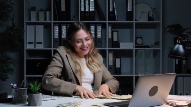 Finansal başarıyı kutlayan, para yağdıran ve akşam ofisinde çalışan Kafkasyalı kadın serbest yazar. Zenginlik ve refah kavramı.