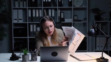 Kızgın kadın Kafkasyalı ofis çalışanı çevrimiçi video görüşmesi yapıyor, laptop ve belgelerle çalışıyor, iş arkadaşlarını azarlıyor veya ofisteki çalışanları azarlıyor..