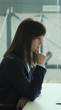 Ofiste dizüstü bilgisayarla çalışan düşünceli, orta yaşlı bir kadın çalışanın ifadelerini ya da bütçesini analiz ediyor. Dikey video.