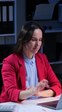 Anlaşmayı tamamlayan ve akşam ofisinde çalışırken başarıyı kutlayan orta yaşlı beyaz kadın serbest yazar. Dikey video.