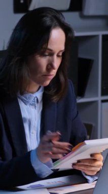 Akşam ofisinde çalışırken not defterine yazan Kafkasyalı bir iş kadını. Zaman çizelgesi ya da gündem oluşturuluyor. Dikey video.