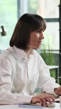 Neşeli Kafkas kadın çalışanı zaferi kutluyor ve ofiste çalışırken haykırıyor. Başarılı bir başarı kavramı. Dikey video.