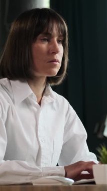 Organize Kafkasyalı orta yaşlı iş kadını bilgisayarla çalışıyor ve ofisteki açıklamaları ya da iş bütçesini analiz ediyor. Dikey video.