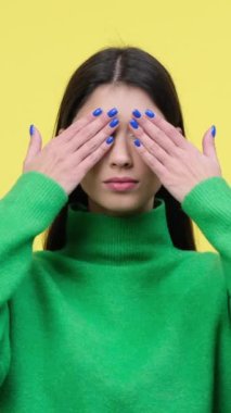 Ciddi bir beyaz kadın, gözleri anlaşmazlıkla kaplıyor ya da sarı arka planda onaylanmıyor. Savunma ya da reddedilme kavramı. Dikey video.