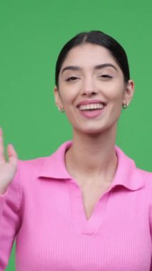 Sosyal medyaya bağlanan mutlu kadın vlogger tartışması ya da diyalog kuruyor, yeşil arka planda duruyor. Dikey video.