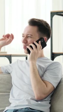 Telefon kullanan, uzaktan konuşma ya da evdeki pazarlıkla meşgul olan, Kafkas asıllı genç bir adam. Tartışma ya da dedikodu kavramı. Dikey video.