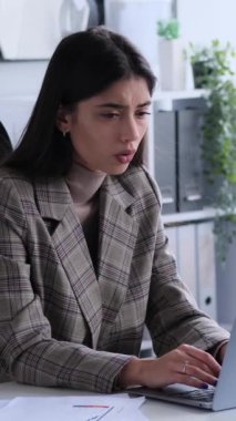 Diz üstü bilgisayarla çalışırken, ofiste masa başında otururken kötü haberlerden rahatsız olan beyaz kadın çalışanlar. Endişe kavramı. Dikey video.