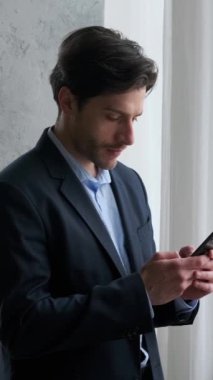Organize Kafkas genç iş adamı cep telefonunu internet işi ve iş iletişimi için kullanıyor. Dikey video.