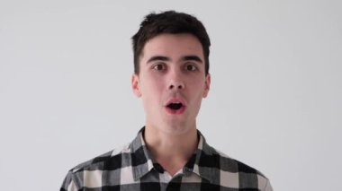 Şaşırmış beyaz bir gencin portresi. Vay canına diyor ve evet, başarıyı beyaz arka planda kutluyor. İyi haber, başarı konsepti..