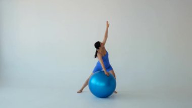 Mutlu ve hamile orta yaşlı beyaz kadın hamilelik pilates eğitimi sırasında beyaz arka planda vücut esneme hareketleri yapıyor..