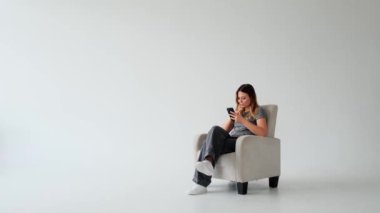 Dost canlısı, genç, beyaz arka planda sosyal medyada mesajlaşmak için akıllı telefon kullanan beyaz bir kadın. İnternet eğlencesini alışveriş ve iletişimle geçirmek.