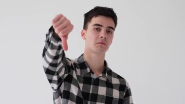 Beyaz arka planda baş parmağını gösteren ya da sevmeyen sert beyaz bir gencin portresi. Anlaşmazlık, inkar, yasaklama kavramı.