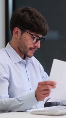 Ofiste çalışırken düşünceli, orta yaşlı bir iş adamı ya da muhasebeci strateji ve düşünme. Dikey video.