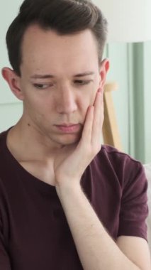 Evdeki kanepede oturan kederli, beyaz, yetişkin bir adamın portresi. Duygusal stres, üzüntü ve depresyon kavramı. Dikey video.