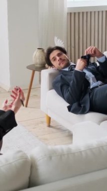 Kadın psikoterapist, ofisteki üzgün beyaz erkek ofis çalışanına yardım ediyor. Kötü ruh sağlığı ve psikoterapi seansı kavramı. Dikey video.