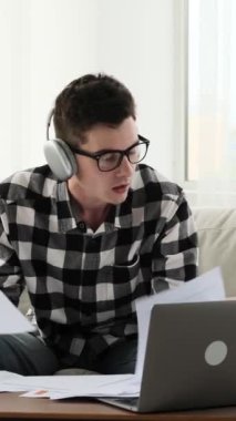 Düşünceli Kafkasyalı genç bir beyaz adamın evde cep telefonuyla internette sohbet etmesi. İnternetteki iletişim kavramı. Dikey video.