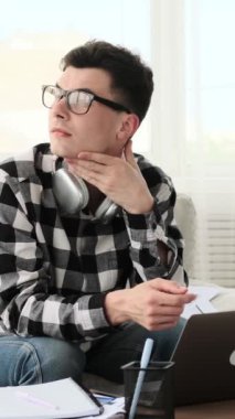 Öfkeli Kafkasyalı genç bir adam, meslektaşlarını azarlıyor. Oturma odasından çalışırken online konferansa katılıyor. Dikey video.