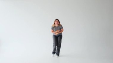 Gülümseyen ve neşeli Kafkasyalı genç bir kadın beyaz arka planda tek başına yüksek sesle gülüyor. İyi ruh hali, memnuniyet ve zevk konsepti.