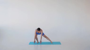 Yoga sırasında beyaz arka planda aktif eğitime eğilip dinlenme ve sağlıkla meşgul olan konsantre hamile orta yaşlı beyaz kadın..