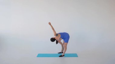 Beyaz arka planda yoga, spor ya da pilates yaparken değirmen egzersizi yapan orta yaşlı, beyaz hamile bir kadın var. Pratik ve eğitim kavramı.