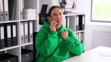 Neşeli Kafkas kadın serbest çalışan arkadaşlarıyla konuşmak için akıllı telefonu kullanıyor, ofis molasında dinleniyor. Uzaktan konuşma ve iletişim kavramı.