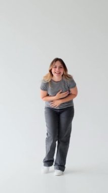 İyimser ve komik beyaz arka planda gülen beyaz bir kadının portresi. Neşeli ruh hali kavramı. Dikey video.