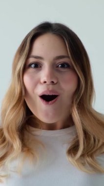 Vay canına diye haykıran ve beyaz arka planda başarıyı kutlayan ezilmiş bir kadının portresi. İyi haber kavramı. Dikey video.