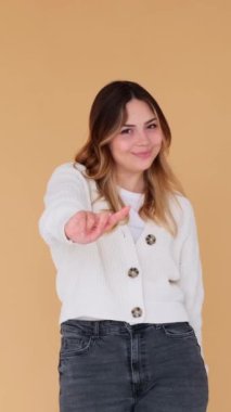Kışkırtıcı beyaz bir kadının bej arka planda duran parmak sallaması portresi. Sataşma ve flört kavramı. Dikey video.