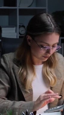 Kafkasyalı genç bir kadının muhasebe işi için hesap makinesi kullandığını ya da ofiste çalışırken ücret hesapladığını düşünmek. Dikey video.