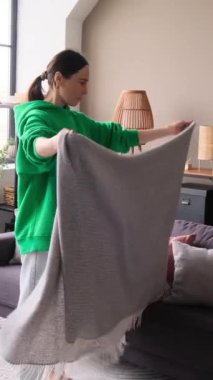 Keyifli orta yaşlı beyaz kadın evdeki oturma odasındaki kanepede sipariş veriyor. Ev işleri ve günlük görevler konsepti. Dikey video.