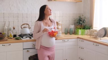 Hamile, beyaz, orta yaşlı kadın salata yiyor, anneliği planlıyor ve doğum hazırlıyor..