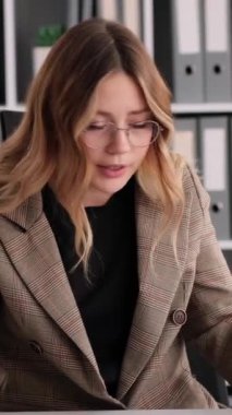 Ofiste çalışırken online görüntülü görüşme ya da toplantı sırasında iş arkadaşlarını azarlayan agresif Kafkasyalı genç bir kadın. Dikey video.