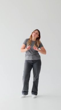 Yorgun ve mutsuz, beyaz arka planda esneyen ve gerinen Kafkasyalı genç bir kadın. Yorgunluk, yorgunluk konsepti. Dikey video.