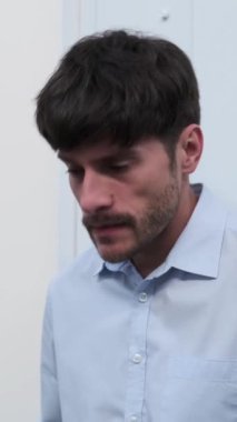 Kafası karışmış orta yaşlı Kafkas çalışanı ofisteki hayal kırıklığı ve stresi ifade ediyor. Umutsuzluk, yorgunluk ve hüsran. Dikey video.