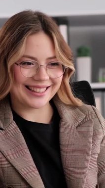 Kafkasyalı genç, neşeli, yetişkin bir ofis çalışanının portresi. Mola sırasında boş zamanlarını telefonda sohbet ederek geçiriyor. Dikey video.