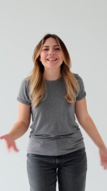 Neşeli ve aktif Kafkasyalı genç kadın blog yazarı beyaz arka planda durarak çevrimiçi sosyal medyada canlı yayın yapıyor. Dikey video.